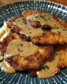 some fried chicken with gravy on top of mashed potatoes and gravy