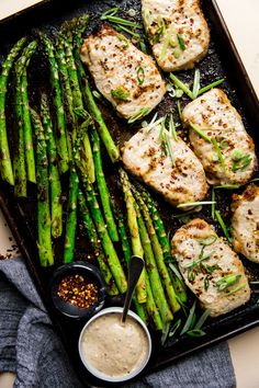 grilled chicken and asparagus with ranch dressing on a baking sheet, ready to be served