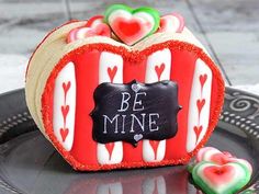 a heart shaped cookie with candy hearts on it and the words be mine written in black