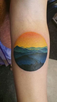 a colorful sunset tattoo on the arm