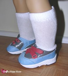 the legs and feet of a person wearing blue shoes with red bows on them, standing in front of a white wall