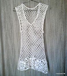 a white crochet top hanging on a wall