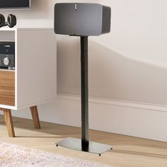 a speaker stands in front of a tv on a stand next to a bookcase