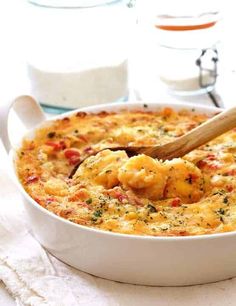 a white bowl filled with food on top of a table next to a wooden spoon