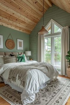 a bedroom with green walls and wood ceilinging, white bedding, and large windows