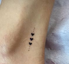 a small black heart tattoo on the left side of the ankle, with three smaller hearts drawn