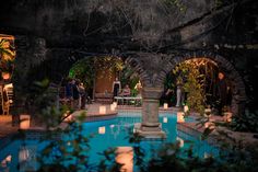 an outdoor pool with candles lit in the middle and people sitting at tables around it