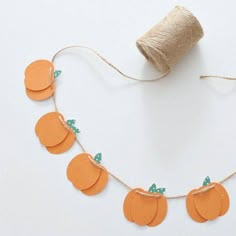 an orange string with paper pumpkins on it and twine spool attached to the string