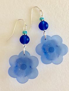 "Beautiful light sapphire blue or royal blue sea glass flowers are the feature of these pretty dangle earrings. Large 1\" sea glass flower is accented with contrasting shades of royal blue, teal and aqua blue sea glass rounds. Earrings are made of cultured tumbled sea glass and wire wrapped in German silver plated jeweler's wire. They hang from silver plated ear wires. Light sapphire blue earrings measure 2\" long and royal blue are 2 1/4\" long. Also available in Sterling silver. Listing is for Sea Glass Flowers, Sapphire Blue Earrings, Glass Flower Earrings, Pretty Earrings Dangle, Earrings Beach, Light Sapphire, Blue Sea Glass, Glass Light, Glass Flowers