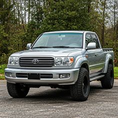 a silver truck parked in front of some trees