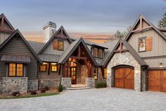 a large house with stone and wood trimmings on the front, two garage doors are