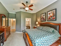 a bedroom with a bed, dresser, and ceiling fan in it's center