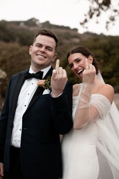 a bride and groom posing for a photo with their fingers in the air while holding up two peace signs