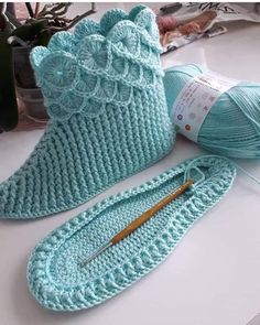 crochet booties and knitting needles sitting on a table