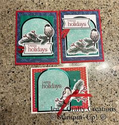 three christmas cards on a table with a red ribbon around the edges and one has a bird