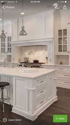 a large kitchen with white cabinets and marble counter tops, along with an island in the middle