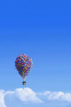 a hot air balloon floating in the sky with many colors on it's tail