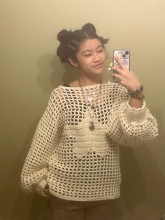 a woman taking a selfie in front of a mirror wearing a sweater and pants