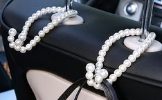 a white beaded necklace is attached to a car seat