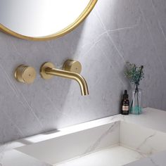 a bathroom sink with a gold faucet and marble counter top next to a round mirror