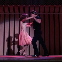 two people are dancing on stage with their arms around each other