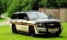 a black and white police car parked in the grass near a sign that says nathan trace parkway