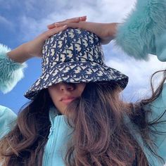 a woman with long hair wearing a blue hat and fur pom - poms