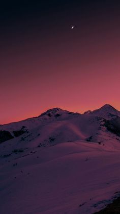 the moon is setting over some snowy mountains