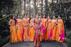 a group of women standing next to each other in orange and pink sari dresses