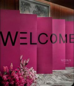 pink paper bags with the word welcome written on them and flowers in front of it