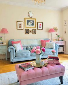 a living room filled with furniture and pink flowers on top of a coffee table in front of a blue couch