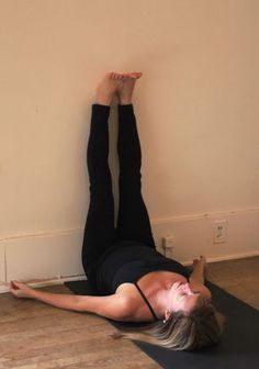 a woman laying on the floor with her feet up and arms behind her head as she stretches