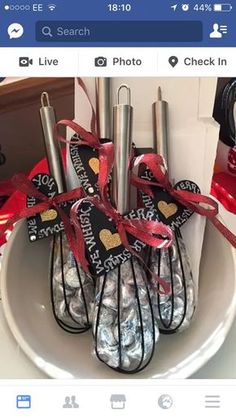 a white plate topped with lots of candy covered in red and black ribbon next to two metal utensils