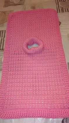 a pink crocheted blanket laying on top of a bed