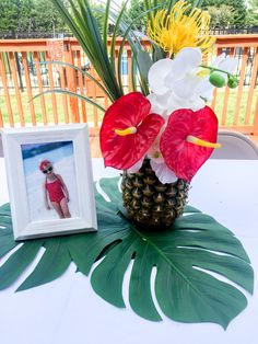 a pineapple vase with flowers in it next to a photo frame on a table