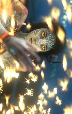 a woman is floating in the water surrounded by fireflies and stars as she looks at the camera