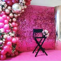 a pink room with balloons and flowers on the wall, next to a folding chair