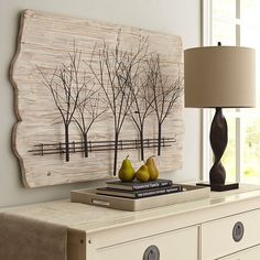 two pears are sitting on top of a dresser next to a lamp and painting