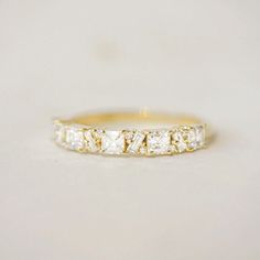 a yellow gold ring with three princess cut diamonds on the side, set in 18k white gold