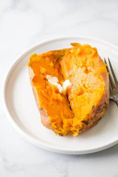 a white plate topped with a piece of baked sweet potato next to a knife and fork