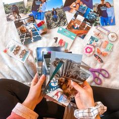 a person is holding photos and scissors on a bed with other items scattered around them