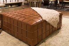 a brown leather ottoman sitting on top of a rug