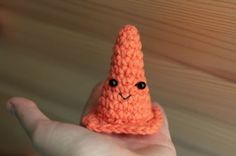 a small orange crocheted object in the palm of someone's left hand