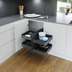 an open drawer in the middle of a kitchen counter with plates and bowls on it