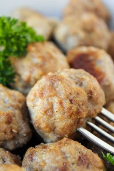 some meatballs and broccoli are on a plate with a fork in it