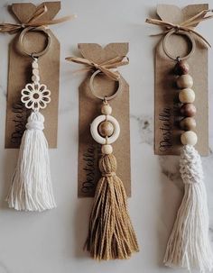 three key chains with tassels and wooden beads hanging from them on brown tags