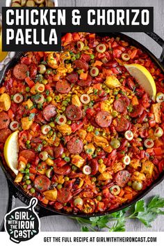 chicken and chorizo paella in a cast iron skillet with lemon wedges