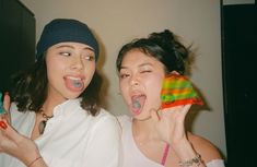 two young women posing for the camera with their mouths open and one holding an object in her hand