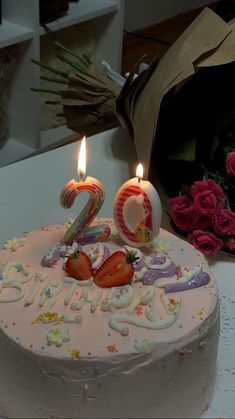 a birthday cake with two candles and strawberries