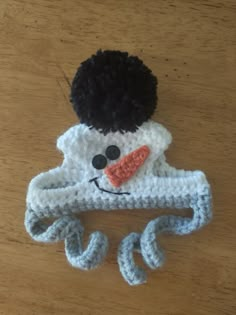 a crocheted snowman hat on top of a wooden table